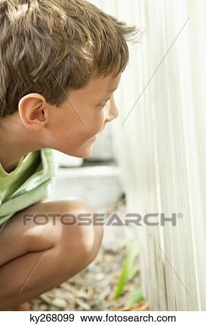 Stock Photo - Boy hiding behind fence. Fotosearch