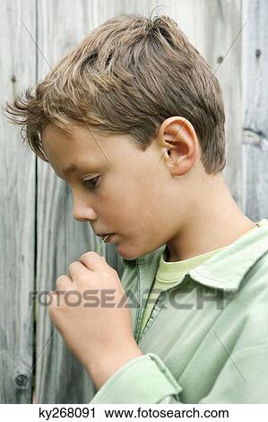 Stock Image - Boy holding a blade of grass in his mouth and smiling. Fotosearch