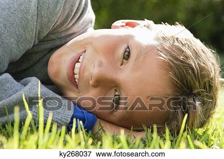 Boy lying on grass and smiling View Large Photo Image Stock Photo - Boy lying on grass and smiling. Fotosearch
