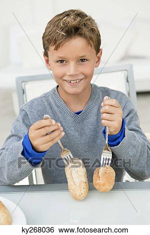 Boy poking forks on breads and smiling View Large Photo Image Stock Photograph - Boy poking forks on breads and smiling. Fotosearch