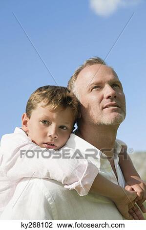Boy riding piggyback on his father View Large Photo Image Stock Image - Boy riding piggyback on his father. Fotosearch