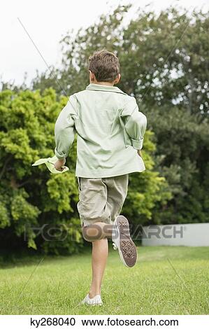 Stock Image - Boy running in a garden with a butterfly net. Fotosearch