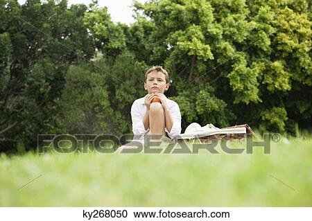 Stock Image - Boy sitting in a park. Fotosearch