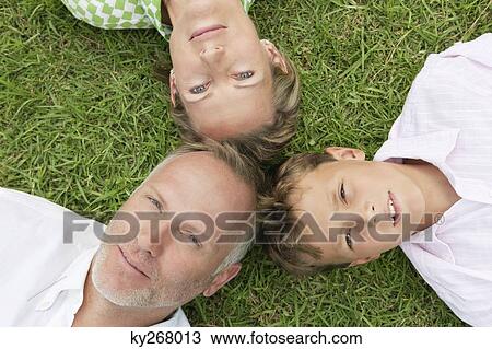 Boy with his parents lying on grass in a park View Large Photo Image Stock Image - Boy with his parents lying on grass in a park. Fotosearch