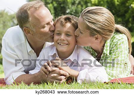 Couple kissing their son in a park View Large Photo Image Stock Image - Couple kissing their son in a park. Fotosearch