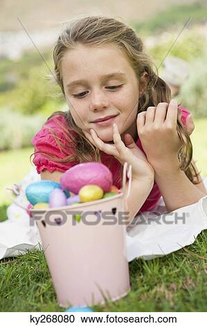 Stock Image - Girl looking at Easter eggs. Fotosearch