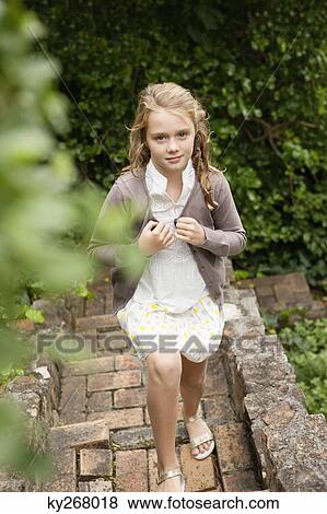 Stock Photo - Girl moving up a staircase in a garden. Fotosearch