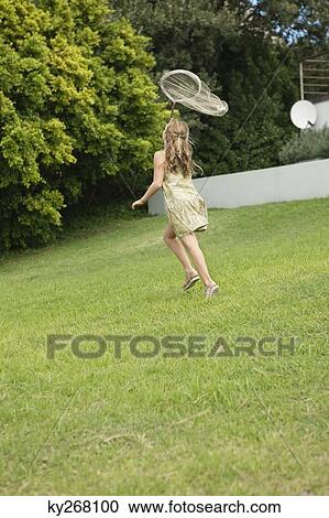 Stock Image - Girl playing with a butterfly net in a garden. Fotosearch