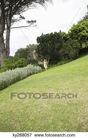 Stock Photo - Girl playing with a butterfly net in a garden. Fotosearch