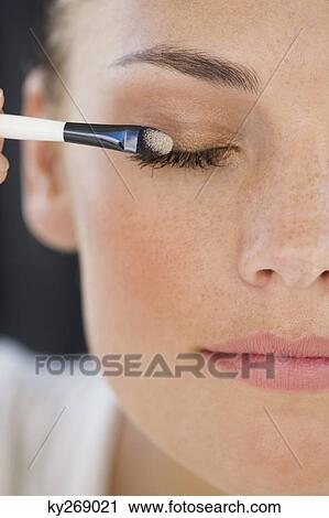 Stock Image - Close-up of a woman applying eye make-up. Fotosearch