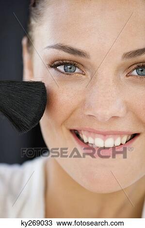 Portrait of a woman applying blusher on her face View Large Photo Image Stock Image - Portrait of a woman applying blusher on her face. Fotosearch