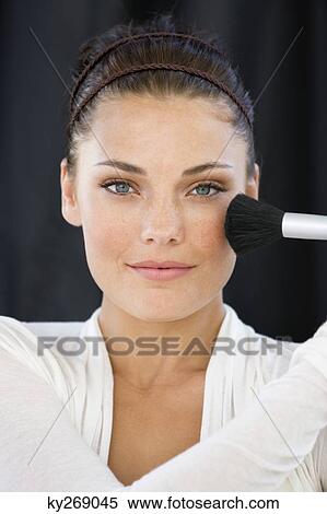 Portrait of a woman applying blusher on her face View Large Photo Image Stock Photography - Portrait of a woman applying blusher on her face. Fotosearch