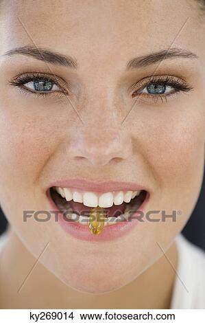 Picture - Portrait of a woman taking an Omega-3 capsule. Fotosearch