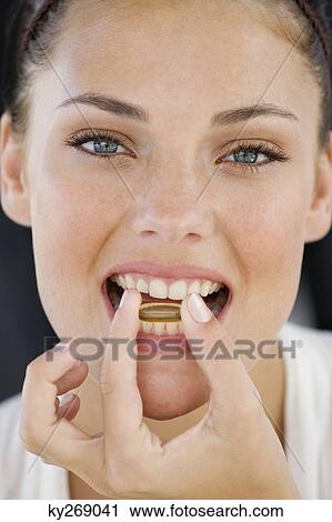 Stock Image - Portrait of a woman taking an Omega-3 capsule. Fotosearch