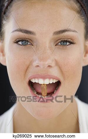 Portrait of a woman taking an Omega-3 capsule View Large Photo Image Stock Photography - Portrait of a woman taking an Omega-3 capsule. Fotosearch