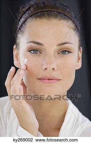 Woman applying cream on her face View Large Photo Image Stock Image - Woman applying cream on her face. Fotosearch
