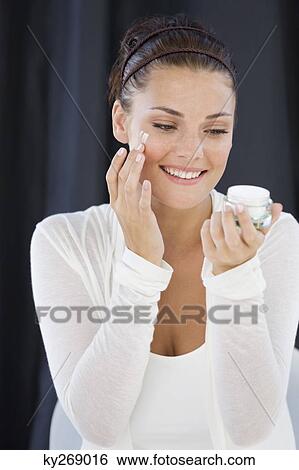 Stock Photograph - Woman applying cream on her face. Fotosearch