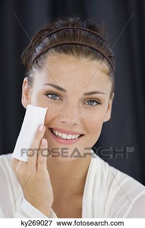 Woman cleaning her face with a tissue paper View Large Photo Image Stock Photo - Woman cleaning her face with a tissue paper. Fotosearch