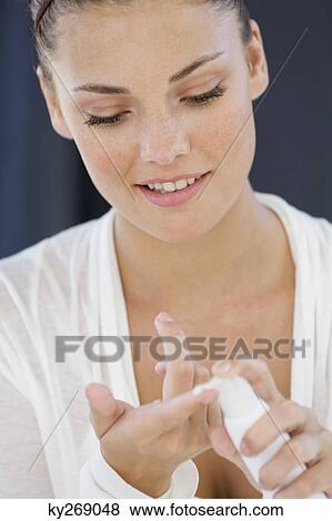 Stock Photo - Woman squeezing out moisturizer from a bottle. Fotosearch