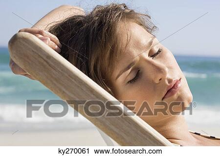 Close-up of a woman resting in a deck chair View Large Photo Image Stock Image - Close-up of a woman resting in a deck chair. Fotosearch