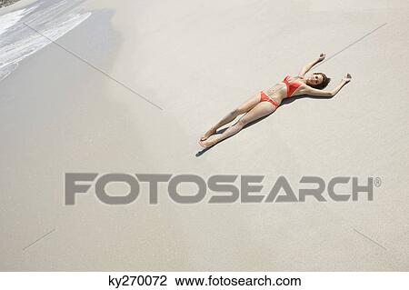 Stock Image - High angle view of a woman lying on the beach. Fotosearch