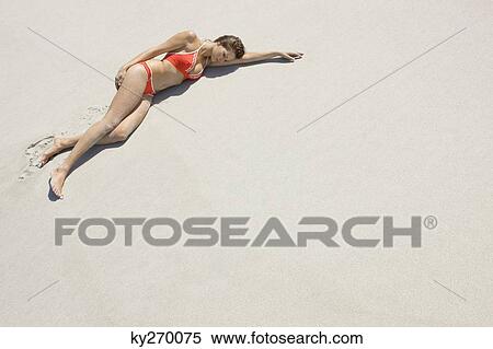 Stock Photography - High angle view of a woman lying on the beach. Fotosearch
