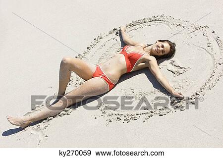 High angle view of a woman making sand angel on the beach View Large Photo Image Stock Photo - High angle view of a woman making sand angel on the beach. Fotosearch
