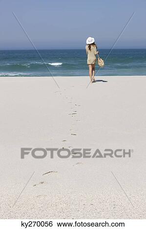 Rear view of a woman walking on the beach View Large Photo Image Stock Photograph - Rear view of a woman walking on the beach. Fotosearch