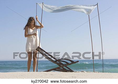 Woman fixing a canopy on the beach View Large Photo Image Stock Image - Woman fixing a canopy on the beach. Fotosearch
