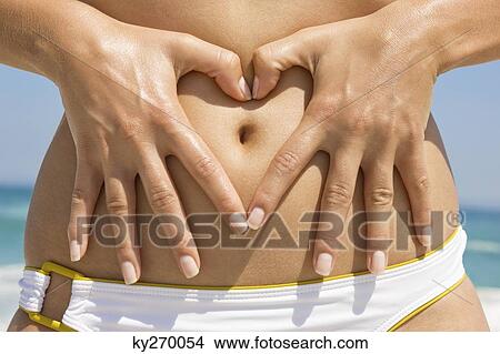 Woman making a heart shape with her finger on her stomach View Large Photo Image Picture - Woman making a heart shape with her finger on her stomach. Fotosearch