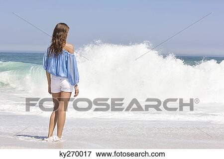 Woman standing on the beach and looking at a view View Large Photo Image Stock Photo - Woman standing on the beach and looking at a view. Fotosearch