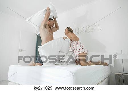 Couple having a pillow fight on the bed View Large Photo Image Stock Photo - Couple having a pillow fight on the bed. Fotosearch