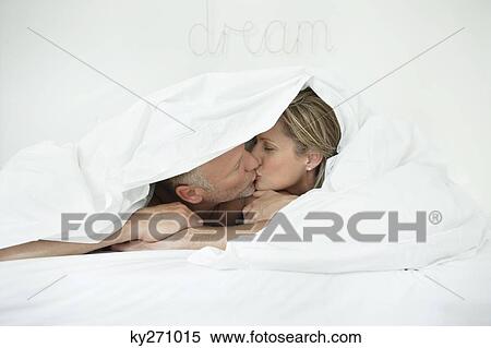 Couple kissing each other under a duvet View Large Photo Image Stock Photography - Couple kissing each other under a duvet. Fotosearch