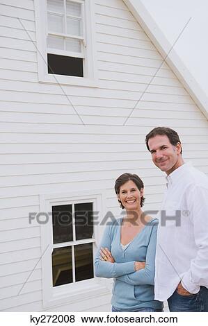 Couple standing together in front of a house View Large Photo Image Stock Photo - Couple standing together in front of a house. Fotosearch
