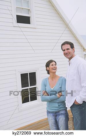 Couple standing together in front of a house View Large Photo Image Stock Photo - Couple standing together in front of a house. Fotosearch