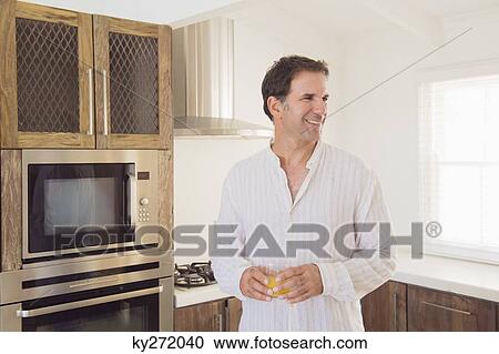 Man holding a glass of juice and smiling View Large Photo Image Stock Image - Man holding a glass of juice and smiling. Fotosearch