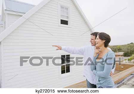 Man pointing towards a house with a woman standing beside her View Large Photo Image Stock Photography - Man pointing towards a house with a woman standing beside her. Fotosearch