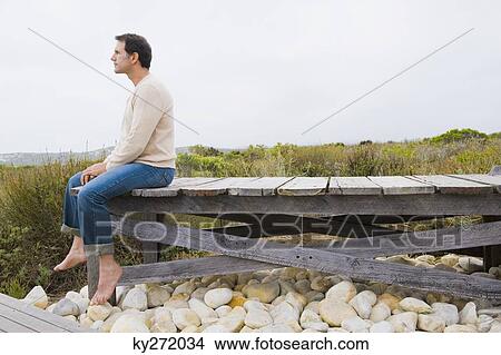 Picture - Man sitting on a boardwalk and thinking. Fotosearch