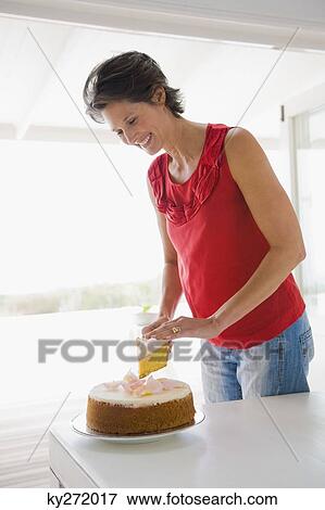 Stock Photo - Woman cutting a cake and smiling. Fotosearch