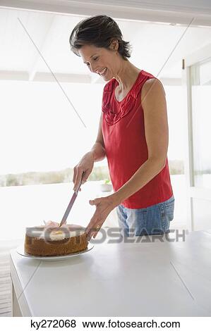 Woman cutting a cake and smiling View Large Photo Image Stock Photo - Woman cutting a cake and smiling. Fotosearch