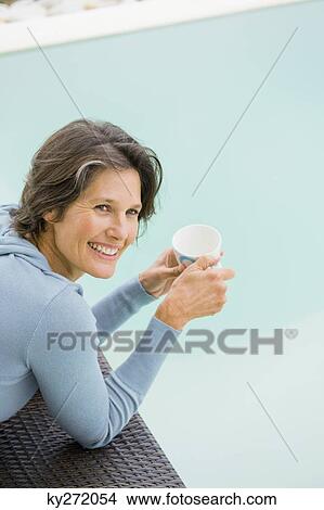 Woman drinking tea at the poolside View Large Photo Image Picture - Woman drinking tea at the poolside. Fotosearch