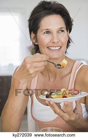 Woman eating fruit salad View Large Photo Image Stock Photo - Woman eating fruit salad. Fotosearch