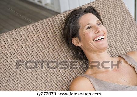 Stock Image - Woman lying on a porch swing and smiling. Fotosearch