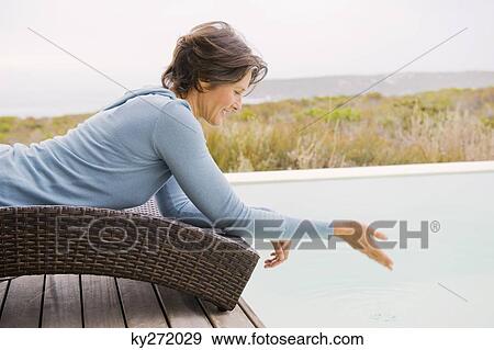 Stock Photo - Woman playing with water at the poolside. Fotosearch