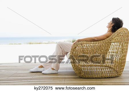 Stock Photography - Woman reclining on a chair on the beach. Fotosearch