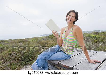 Woman sitting on a boardwalk and reading a book View Large Photo Image Stock Image - Woman sitting on a boardwalk and reading a book. Fotosearch