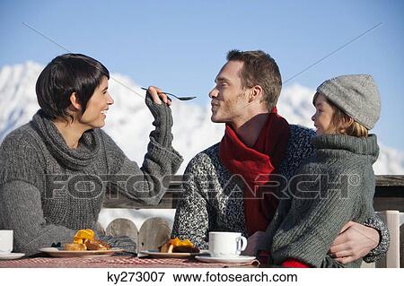 Couple and daughter eating on balcony at ski resort View Large Photo Image Stock Photo - Couple and daughter eating on balcony at ski resort. Fotosearch