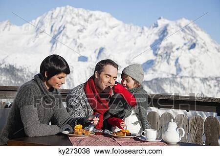 Couple and daughter eating on balcony at ski resort View Large Photo Image Stock Photo - Couple and daughter eating on balcony at ski resort. Fotosearch