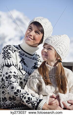 Stock Photo - Mother and daughter on balcony at ski resort. Fotosearch