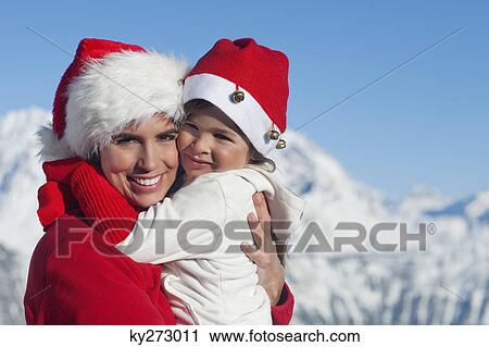 Mother and dauhter wearing Santa hats, hugging View Large Photo Image Stock Image - Mother and dauhter wearing Santa hats, hugging. Fotosearch